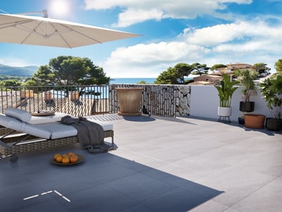 Terraza soleada con tumbonas, sombrilla grande y vistas panorámicas al mar y la montaña.