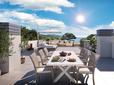 Terraza soleada con comedor exterior, tumbonas y vistas panorámicas al mar y las colinas costeras.