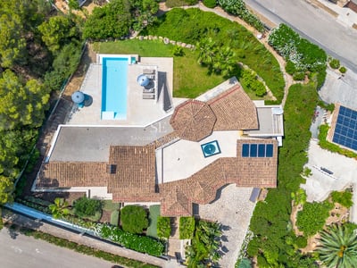 Vista exterior de villa moderna con piscina infinity, jardín y amplias terrazas. Diseño minimalista con grandes ventanales y arquitectura elegante.