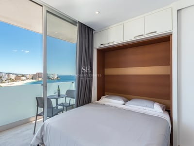 Spacious balcony with a sea view. Modern design, glass railing and wooden floor. Bright and open space.