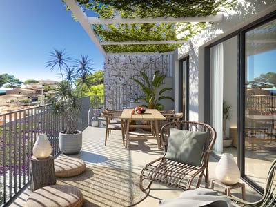 Terraza moderna y soleada con mesa de comedor de madera, sillón de mimbre y pérgola con plantas y vistas a la costa.