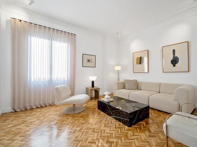 Bright living room with white walls, herringbone wood floors, a beige sofa, and a black marble coffee table.