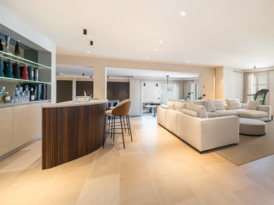 Großzügiges modernes Wohnzimmer mit großem weißen Sofa, Holzbar und Natursteinboden.