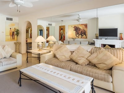 Helles Wohnzimmer mit gestreiften beigen Sofas, Marmorcouchtisch und einer großen Spiegelwand, die Kunstwerke reflektiert.