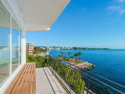 Balkong med träbänk och svart räcke som erbjuder panoramautsikt över det blå Medelhavet och kusten.