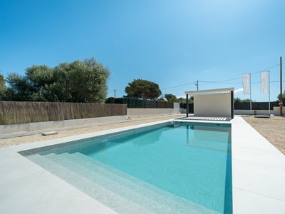 Rectangular turquoise pool with white tile border and a modern white pergola under a clear blue sky.