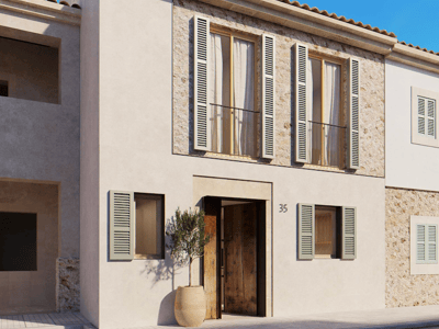 Bâtiment en stuc beige avec volets vert sauge, accents en pierre naturelle et porte en bois sous un ciel bleu.