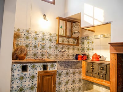 Rustic kitchen featuring hand-painted patterned tiles, a stone sink, and a vintage cast iron wood-burning stove.