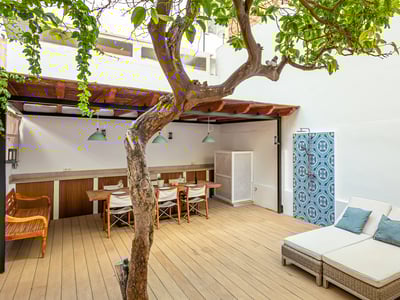 Wooden deck terrace featuring a dining table under a pergola, a large sunbed, and an outdoor shower with blue tiles.