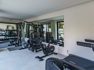 Gimnasio moderno con cintas de correr, bicicleta estática y máquinas de pesas frente a un gran espejo.