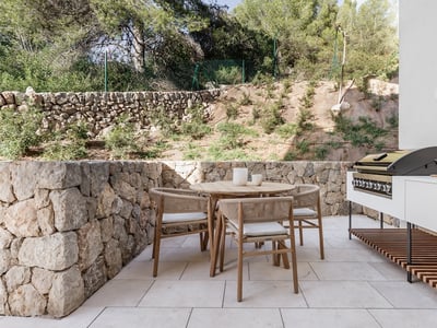 Terrasse mit Holztisch, geflochtenen Stühlen, integriertem Grill und Natursteinmauern.
