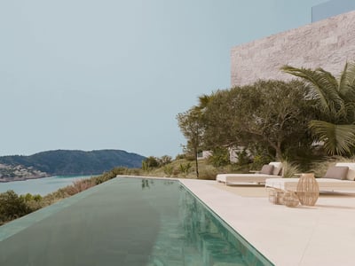 Piscina infinita en terraza de piedra con vistas a una bahía turquesa y colinas verdes bajo un cielo despejado.