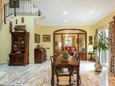 Geräumiges Esszimmer mit gemasertem Marmorboden, klassischen Holzmöbeln und afrikanischer Kunstdekoration.