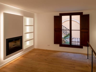 Moderner leerer Raum mit eingebautem Kamin, hinterleuchteten Regalen, Eichenboden und dunklen Holzläden.