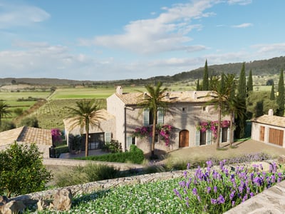 Large rustic stone villa with terracotta roofs, palm trees, and lavender fields under a bright blue sky.
