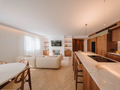 Ljus öppen planlösning med beige soffa, köksö i marmor och varma trägolv.