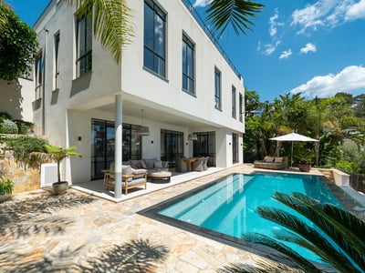 Una luminosa escena exterior con una piscina turquesa, terraza de piedra y una villa blanca moderna.