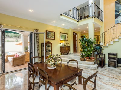 Esszimmer mit Marmorböden, herrschaftlicher Treppe und Zugang zur Terrasse mit Pool.