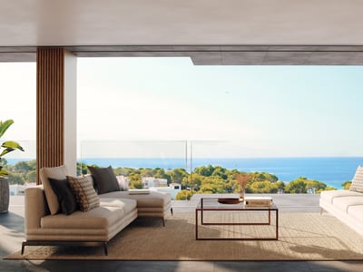 Modern terrass med beige soffor och glasräcke med utsikt över Medelhavet och grönskande natur.