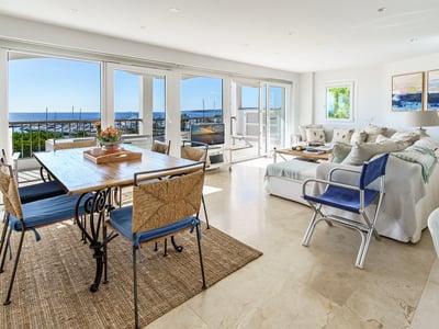 Salon spacieux avec sol en marbre et grandes baies vitrées donnant sur la marina et la mer.