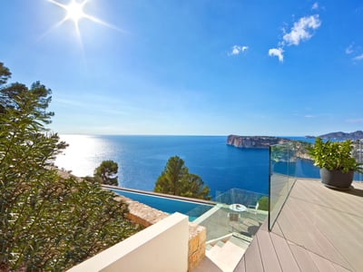 Modern terrass med glasräcke och utsikt över Medelhavet och en infinitypool.