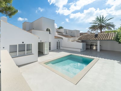 Villa méditerranéenne moderne blanche avec piscine étincelante, terrasse en pierre et cuisine extérieure.