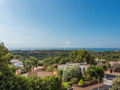 Geräumiges Wohnzimmer mit Meerblick durch Panoramafenster, moderne Möbel, natürliches Licht und neutrale Farbpalette. Elegantes und minimalistisches Design.