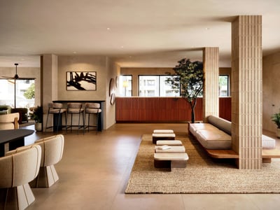 Modern lobby with fluted columns, low seating, a woven rug, and warm terracotta accents in a minimalist setting.