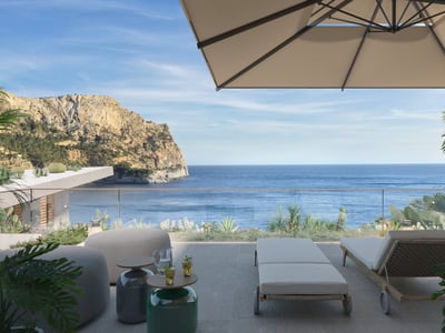 Terraza soleada con tumbonas, sombrilla y barandilla de cristal con vistas al mar Mediterráneo y un acantilado rocoso.