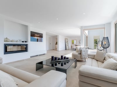 Helles Wohnzimmer mit cremefarbenen Sofas, schwarzem Glastisch, Einbaukamin und großen Panoramafenstern.