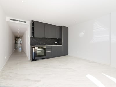 Moderner Küchenbereich mit dunkelgrauen Schränken, schwarzer Marmorrückwand und weißen Marmorböden in einem hellen Raum.