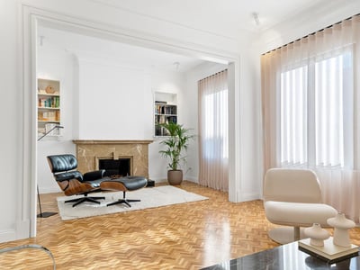 Bright living room with herringbone floors, a marble fireplace, and an Eames chair.