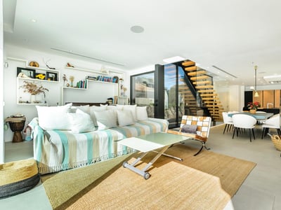 Salón luminoso con sofá de rayas, escalera flotante de madera y chimenea moderna negra.