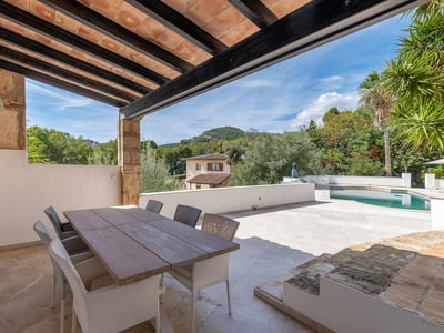 Außen-Essbereich unter Pergola mit Blick auf Pool, Garten und Hügel.