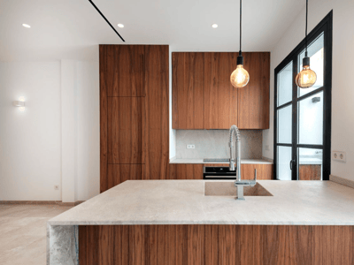 Moderne Küche mit eleganten Walnussholzschränken, Steininsel mit Spülbecken und Designer-Pendelleuchten.