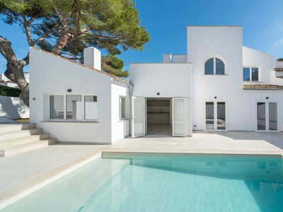 Piscine turquoise devant une villa blanche moderne au style méditerranéen sous un ciel pur.