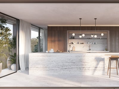 Köksö i travertin med träpallar i ett modernt rum med stora fönsterpartier och träpaneler.