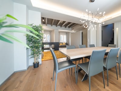 Spacious modern dining room featuring a large wooden table, grey chairs, and a branch-style designer chandelier.