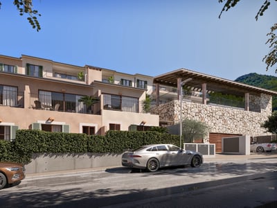 Vista exterior de una villa mediterránea moderna con muros de piedra, balcones y setos verdes bajo un cielo azul.