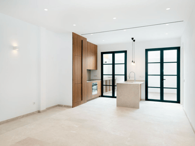 Moderne Küche mit Holzschränken, Steininsel und großen schwarz gerahmten Glastüren, die zur Terrasse führen.