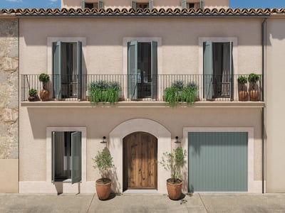 Three-story facade with beige stucco walls, sage green shutters, wrought iron balcony, and arched wooden door.