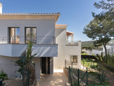 Tvåvånings modern villa med vit fasad, takpannor i terrakotta och balkong under en klarblå himmel.