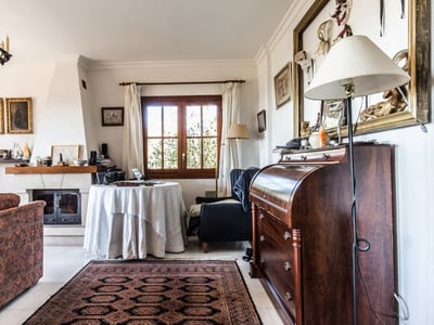 Gemütliches Wohnzimmer mit gemustertem Sofa, Kamin, Orientteppich und antikem Sekretär aus Holz.