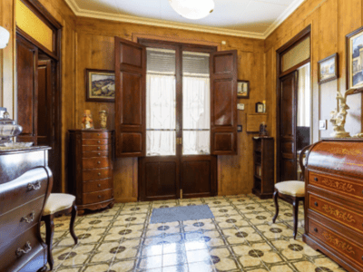 Eingangshalle mit Holzwänden, gemusterten Fliesen und klassischen antiken Möbeln.