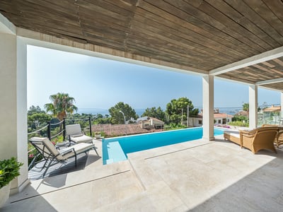 Covered terrace featuring a turquoise pool, sun loungers, and panoramic sea views under a rustic wooden ceiling.