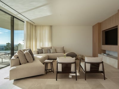 Modern living room with a beige sectional sofa, wood paneled TV wall, and floor-to-ceiling windows with a scenic view.