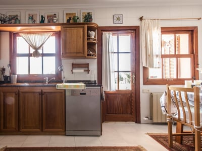 Helle Küche mit warmen Holzschränken, weißen Fliesen, Granitarbeitsplatten und Holzfenstern.