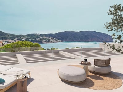 Terraza moderna con tumbonas y asientos de exterior con vistas a una bahía turquesa y montañas verdes.