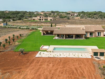 Flygfoto av en lyxvilla med terracottatak, rektangulär pool och stor grön gräsmatta.