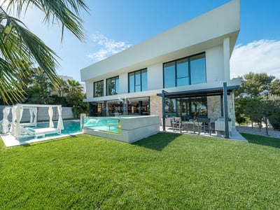 Spacious living room with panoramic windows, ocean view, light wood floors, fireplace, and modern furniture in neutral tones.